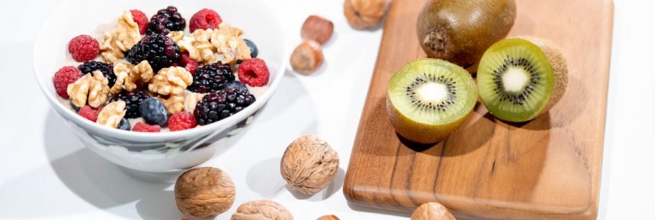 A vibrant bowl of mixed berries, walnuts, and kiwi on a cutting board. Perfect for a healthy breakfast.